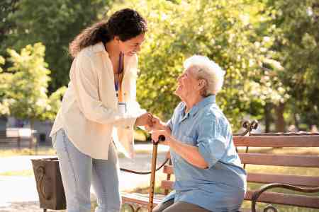 Alte Dame auf Bank und Pflegerin
